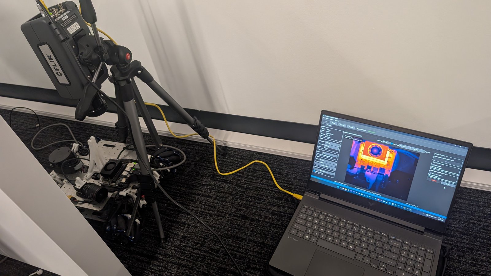 FLIR thermal camera on a tripod imaging a Jetson robot platform, live thermal view on a laptop